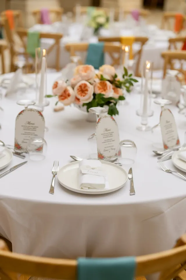 Table dressée avec menus, bougies et roses pêche