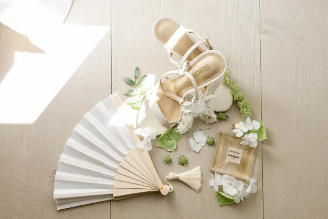 Chaussures de mariée et éventail posés sur le parquet du mas
