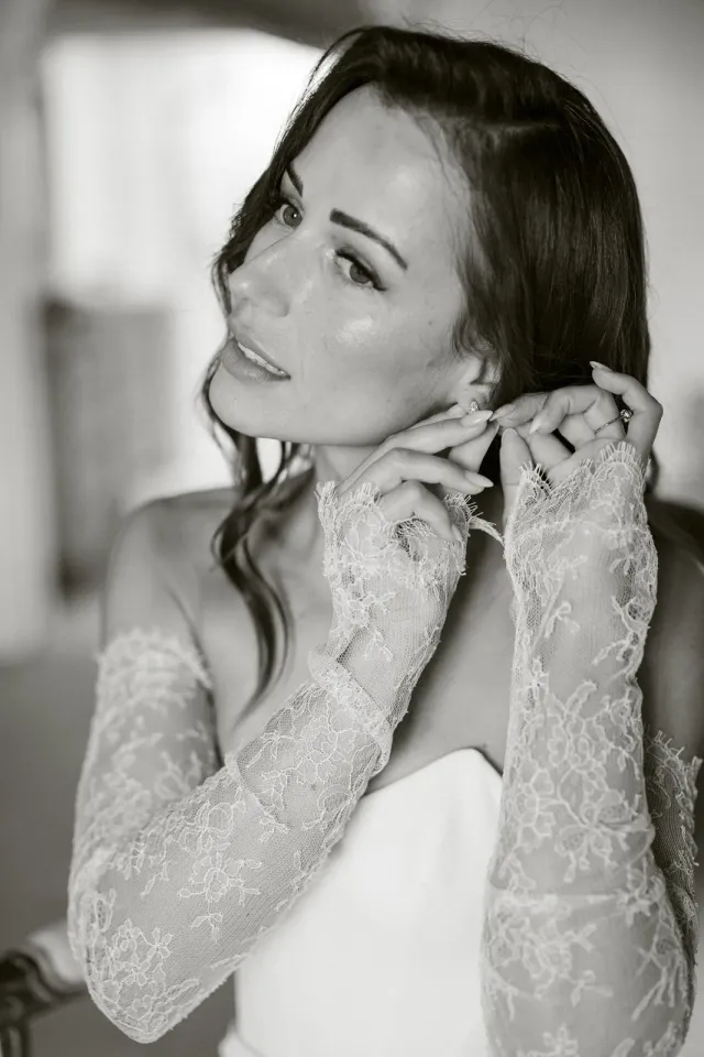 Portrait noir et blanc de la mariée mettant ses boucles d'oreilles