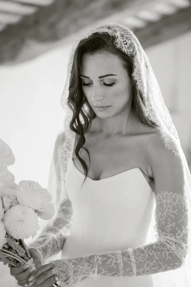 Portrait noir et blanc de la mariée avec son voile brodé et son bouquet