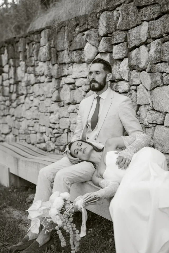 Portrait de couple en noir et blanc contre un mur en pierre sèche
