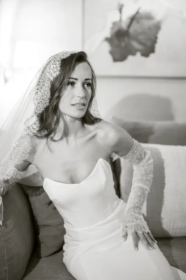 La mariée assise avec son voile brodé au retour du cocktail