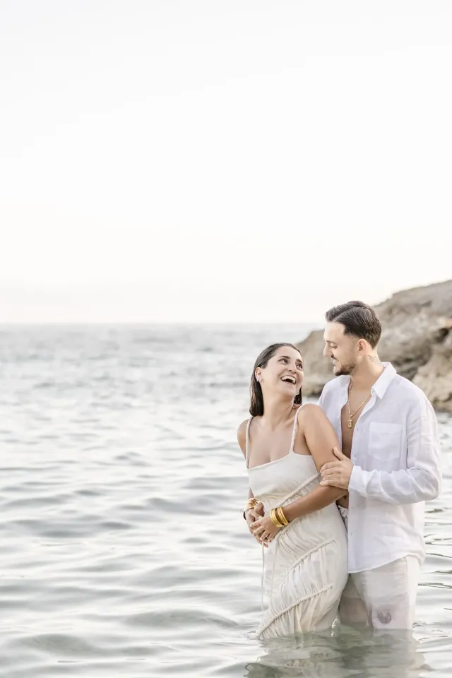Couple swimming fully dressed during their engagement session in Sausset-les-Pins