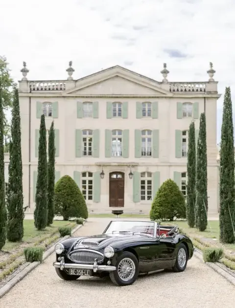 Façade du Château de Tourreau et voiture ancienne dans l'allée de cyprès