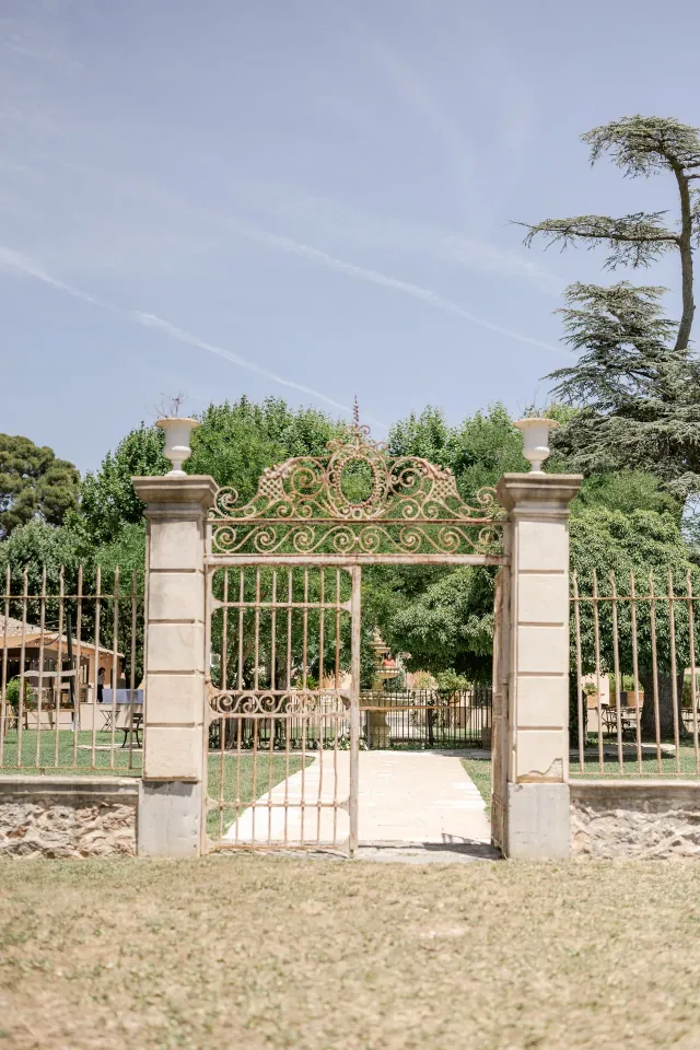 Portail en fer forgé et piliers en pierre à l'entrée du domaine