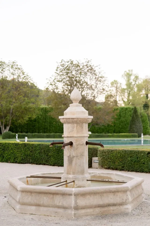 Fontaine en pierre ancienne dans les jardins taillés du Château du Griffon