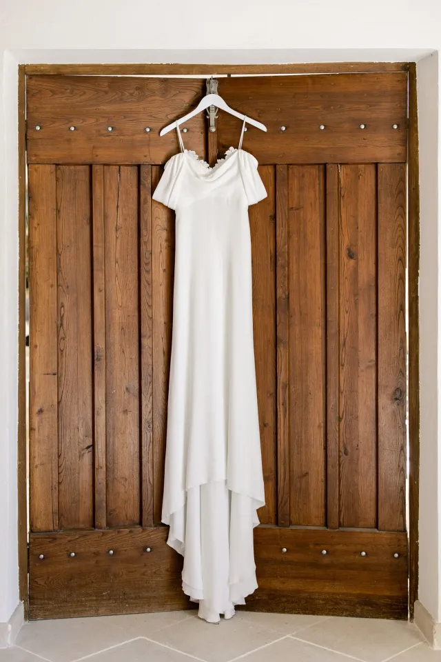 Robe de mariée suspendue devant une porte en bois ancienne
