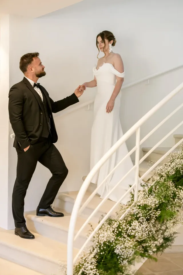 Le marié aide la mariée à descendre l'escalier en fer forgé