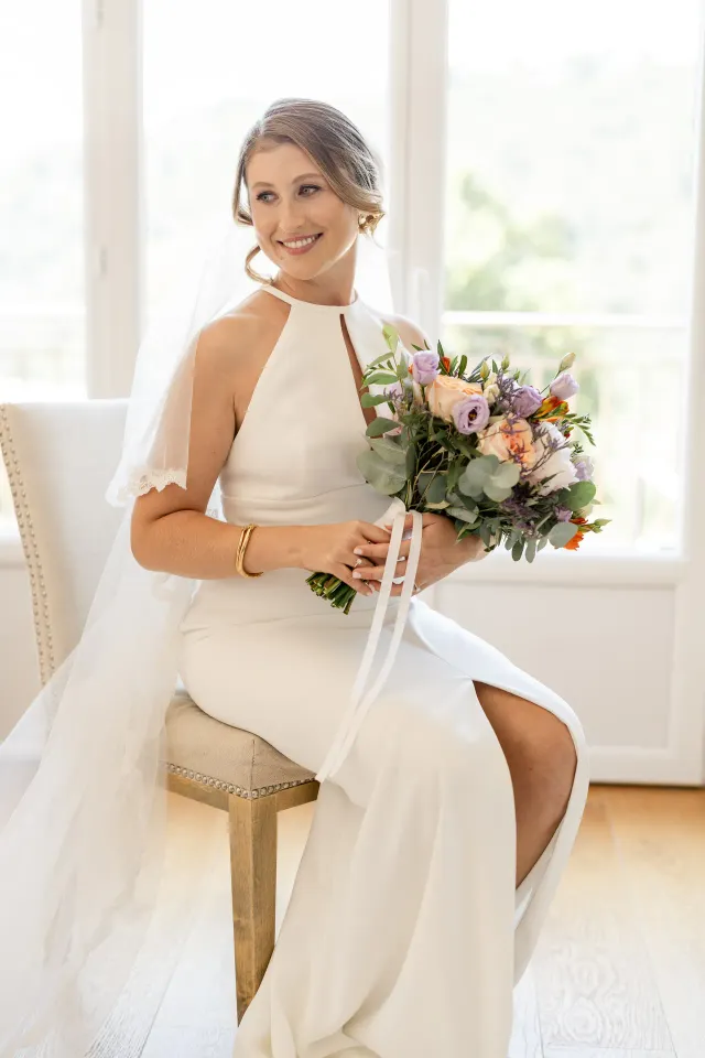 The bride seated holding her pastel-toned bouquet
