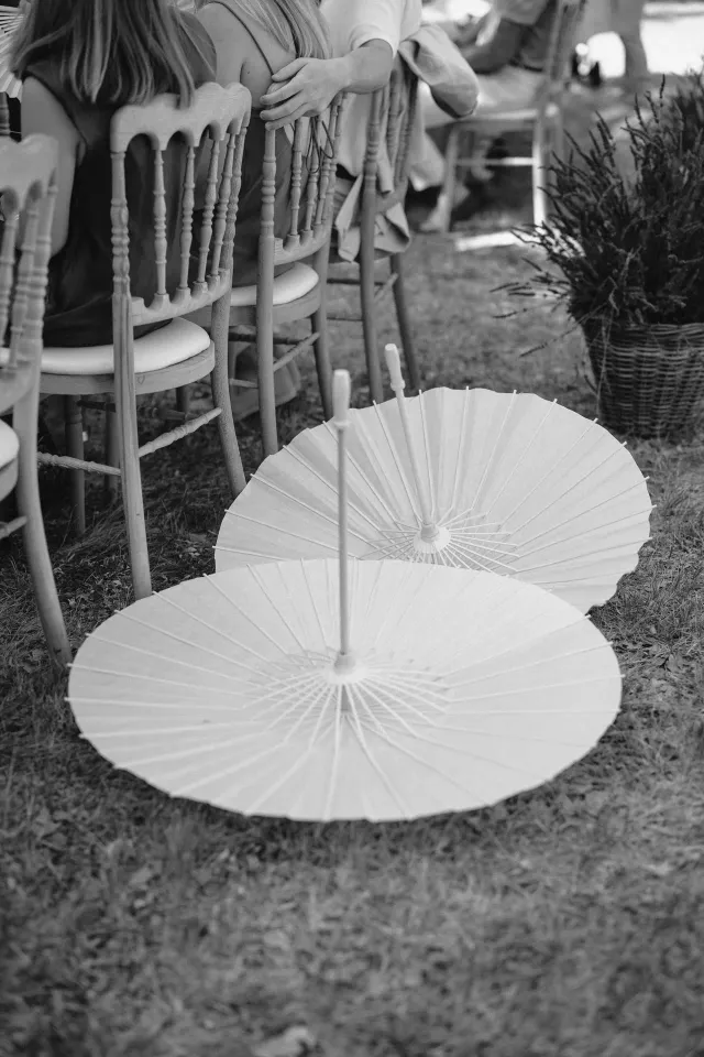 Folded white parasols beside the ceremony, black and white