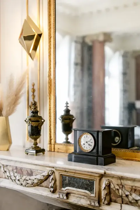 Antique clock and objects on a château drawing room mantelpiece