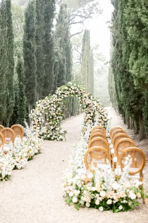 Flower-lined ceremony aisle beneath the cypresses at Château Martinay