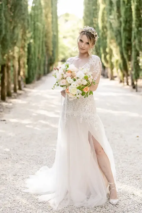 The bride in the cypress avenue, bouquet in hand