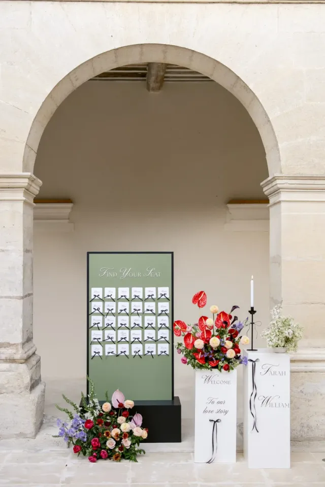 Plan de table et composition florale rouge sous les arcades