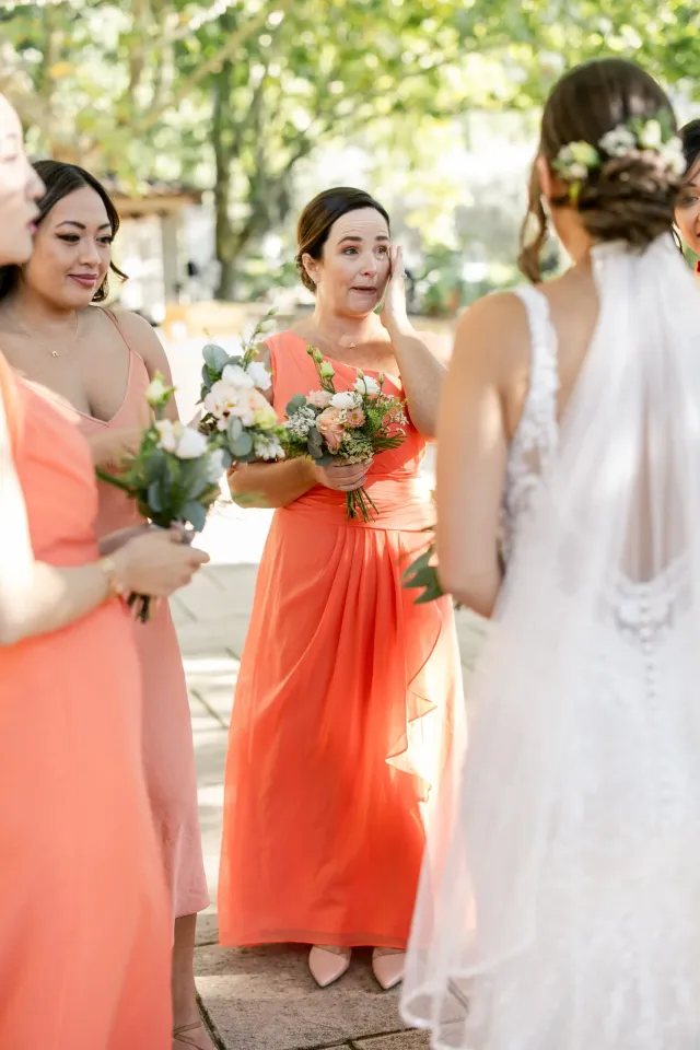 Bridesmaids in coral dresses holding their bouquets