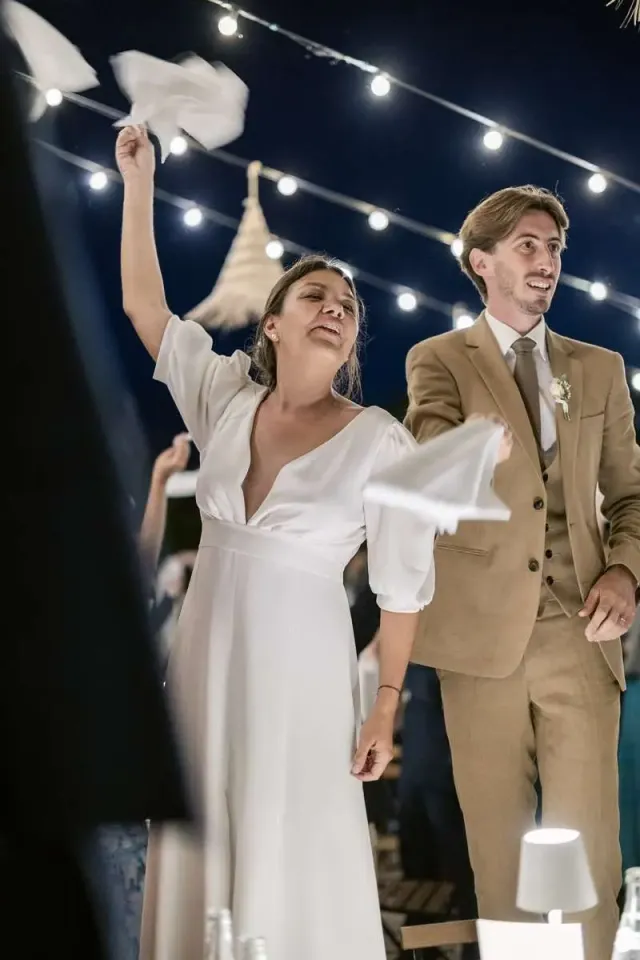 Bride and groom twirling napkins under string lights, festive evening at an intimate wedding