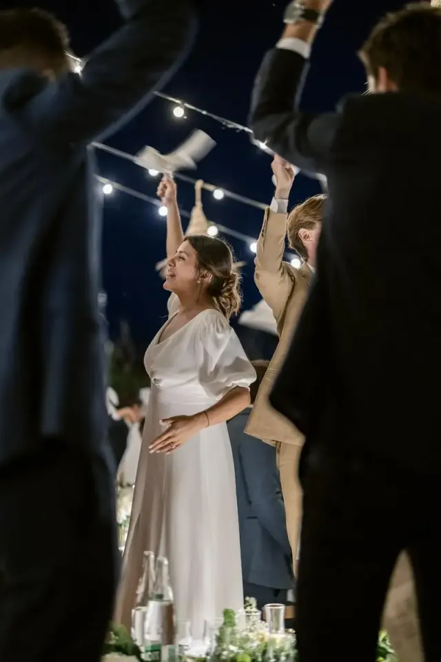 Bride laughing among dancing guests under festoon lights
