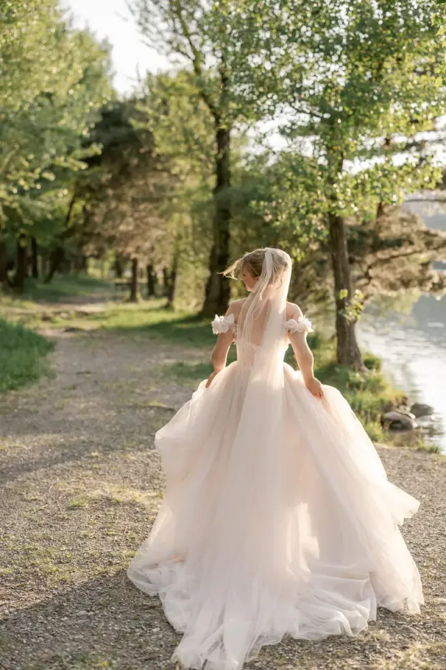 Bride walking alone under the trees in soft late afternoon light in Provence